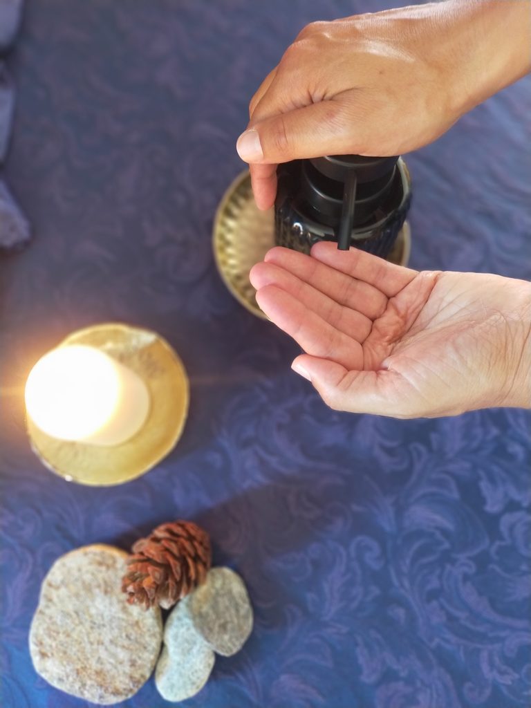 Mains préparant l’huile de massage dans l’univers EPIPHANIA.